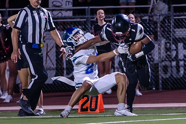 Football players collide near yard marker during intense nighttime play.