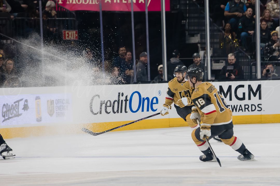 NHL hockey player in yellow jersey falls on the ice during an intense game moment.