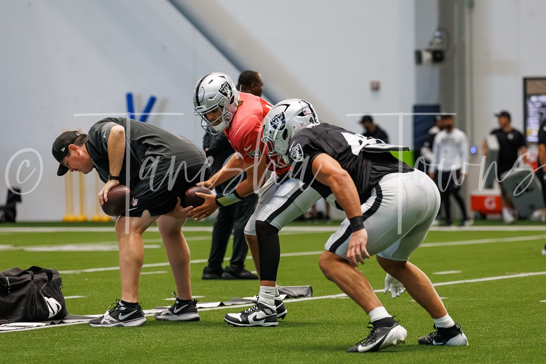 Las Vegas Raiders football players practice drills in an indoor facility during NFL training camp.