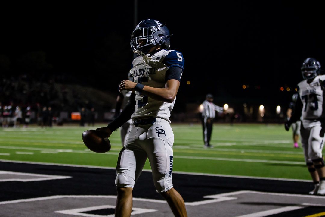 Football players line up near the sideline during a nighttime match.