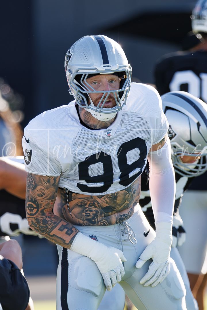 Tattooed Raiders player #98 in white uniform focuses during NFL training camp practice.