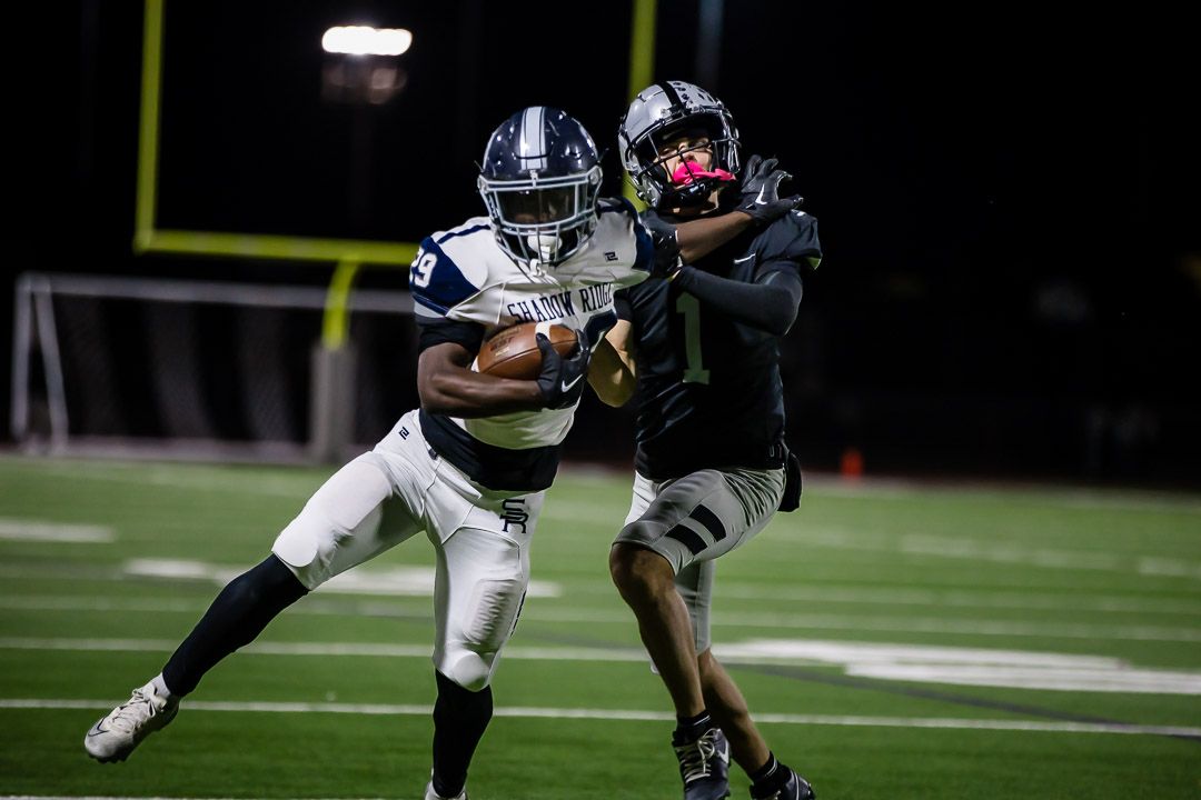 Running back carries the ball while evading defenders on the football field.