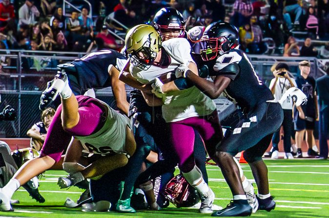 Football players from opposing teams engage in physical struggle during goal line play.