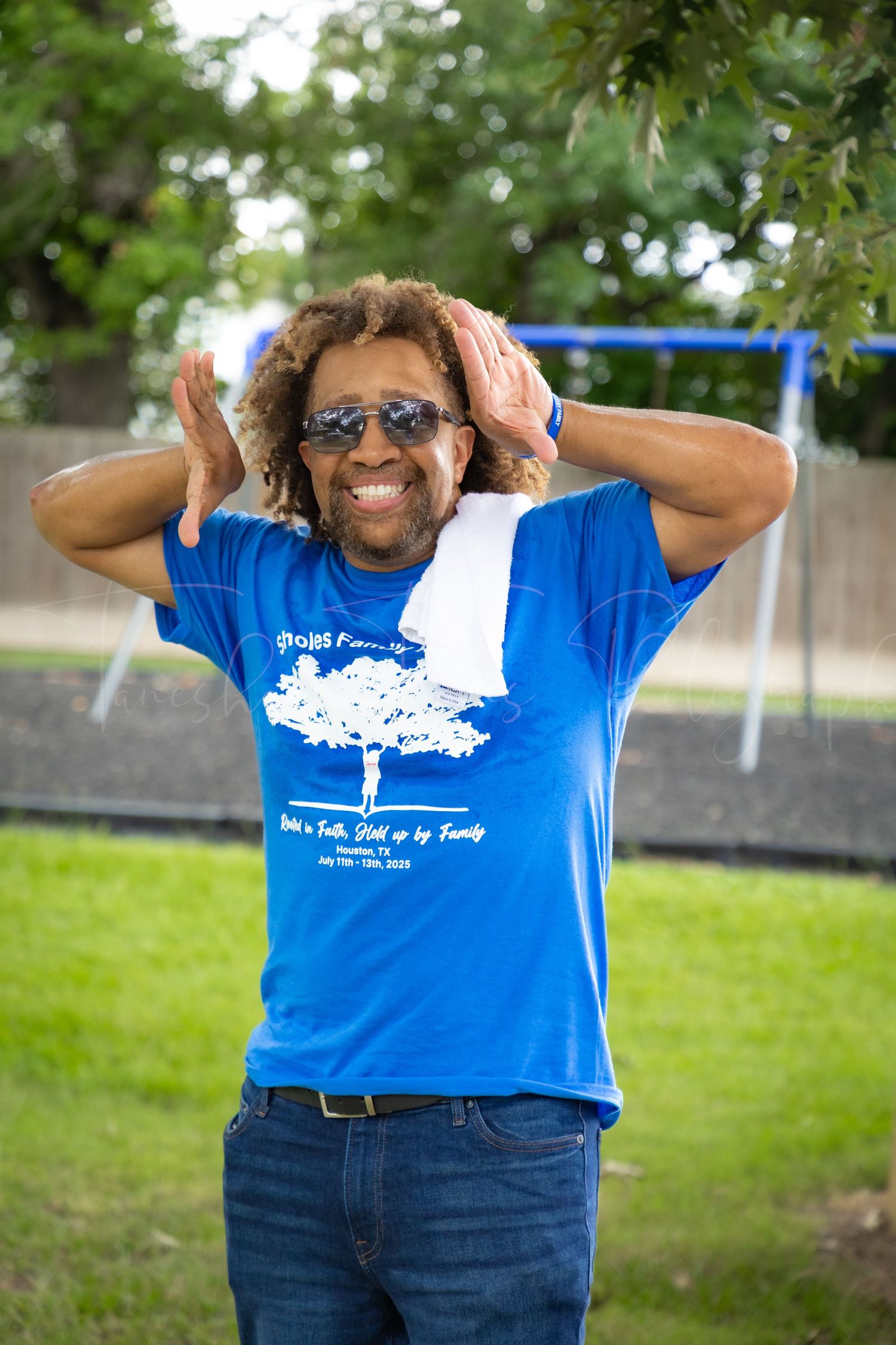 Person in blue t-shirt and jeans poses outdoors at a family gathering.