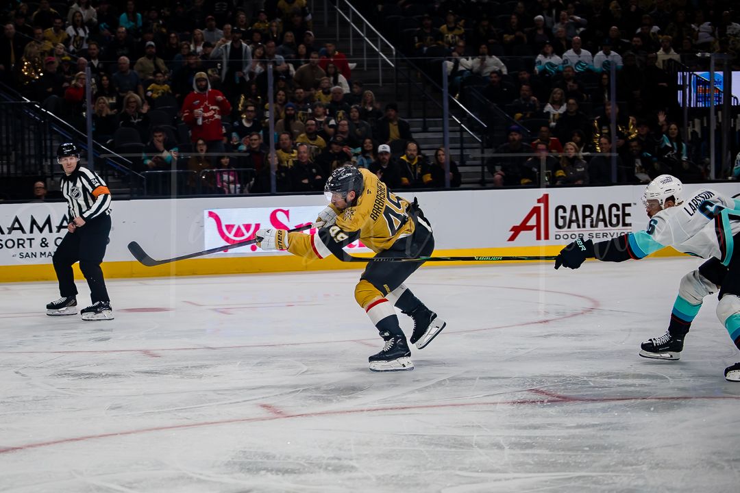 Hockey players from opposing teams skate after the puck during an intense game moment.