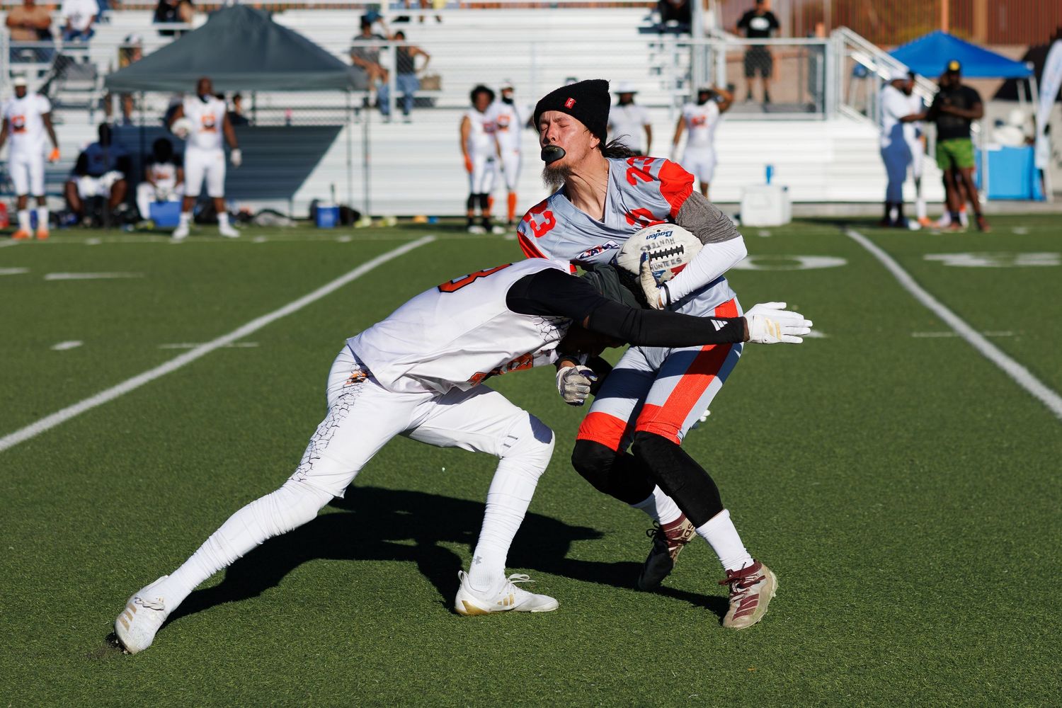 Two players in costumes compete in a flag football game on a green turf field during an outdoor event.