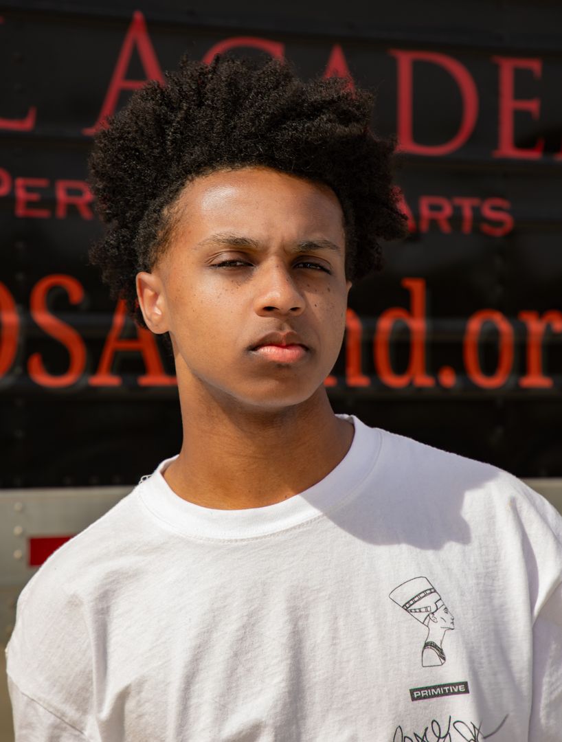 Person in white t-shirt photographed against dark background with red illuminated signage.