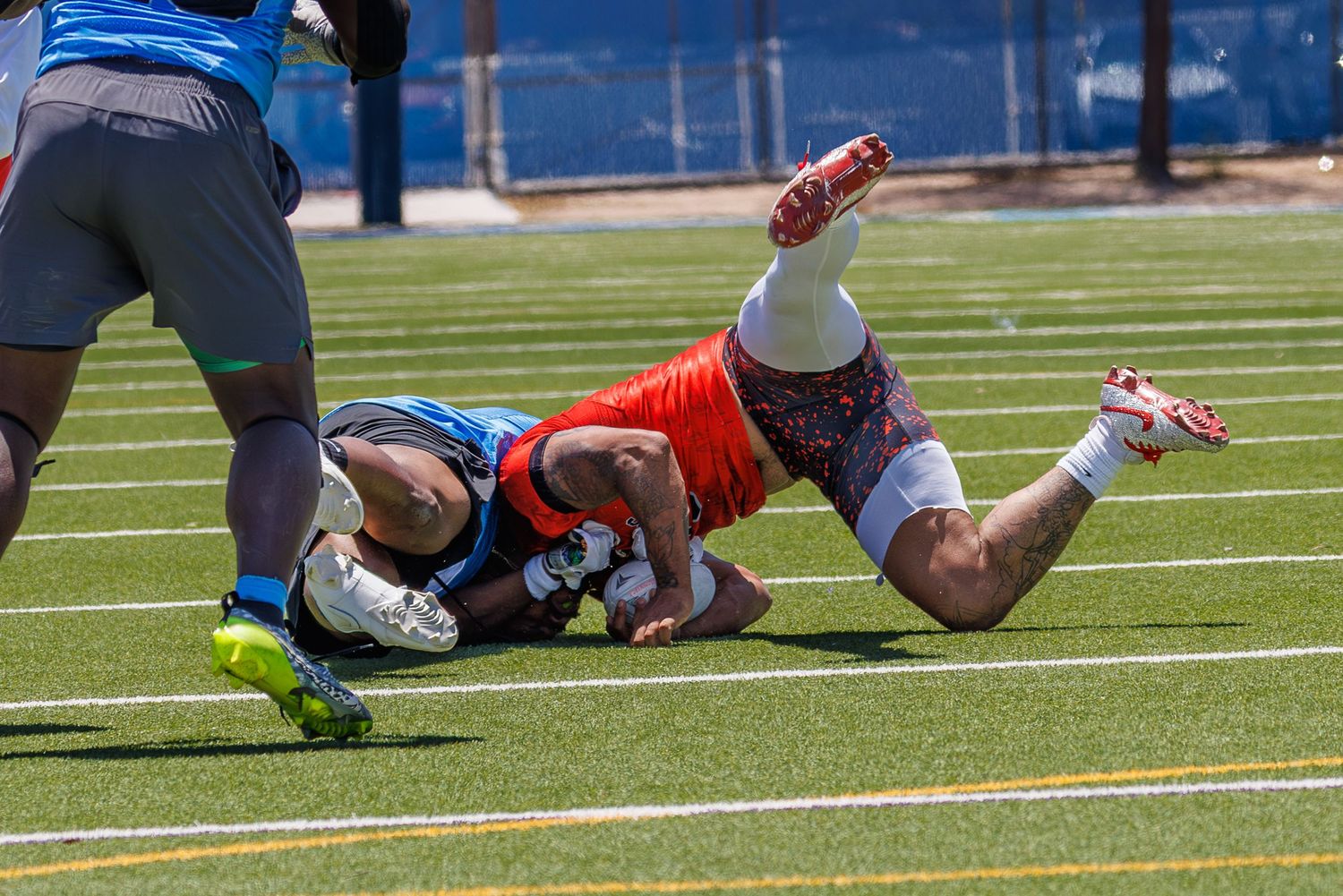 Two football players collide on a turf field during an intense tackle in a competitive outdoor game.