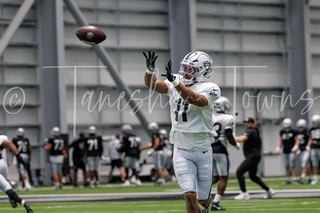 Raiders player #11 catches a football during indoor practice at training facility.