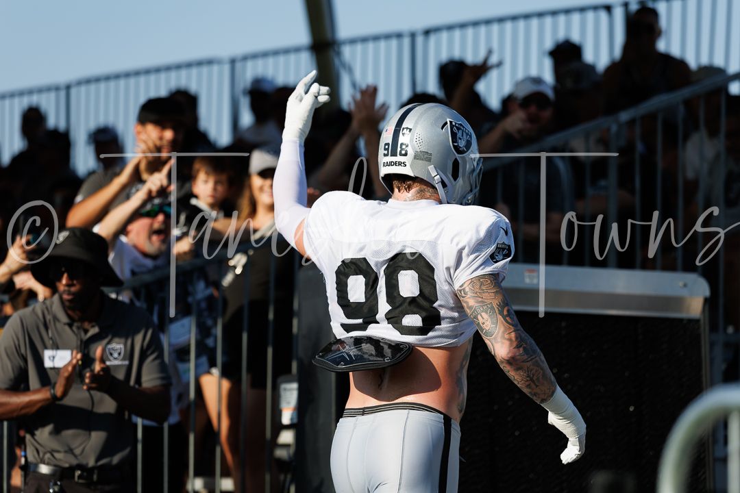 Las Vegas Raiders player #98 celebrates with fans during outdoor training camp practice.