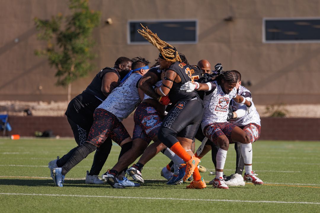 Athletes in a intense rugby scrum battle for possession on a green field during a competitive match.