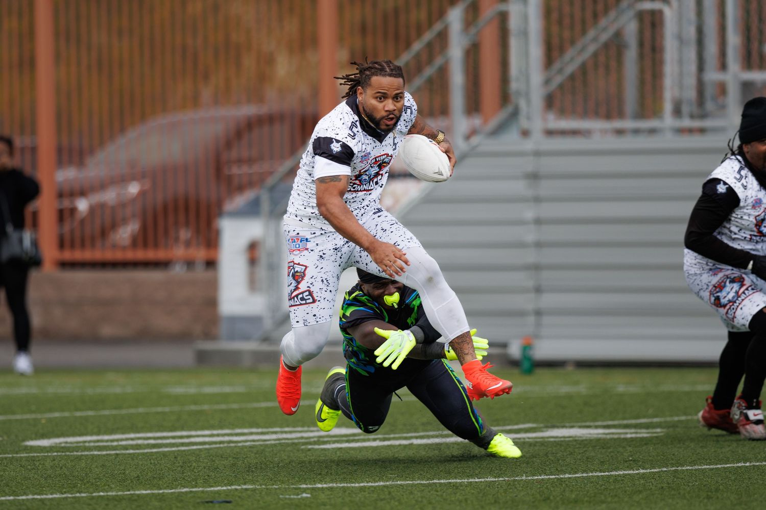 Athletes compete in a flag football game on a green turf field, with one player evading a tackle.