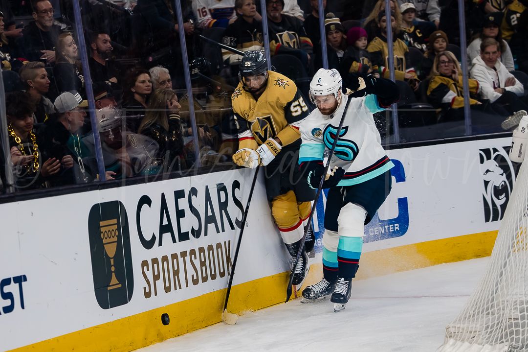 Hockey players from opposing teams battle for position along the boards during an NHL game.