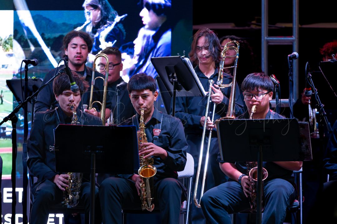 Jazz band members playing saxophones and brass instruments during a live performance.