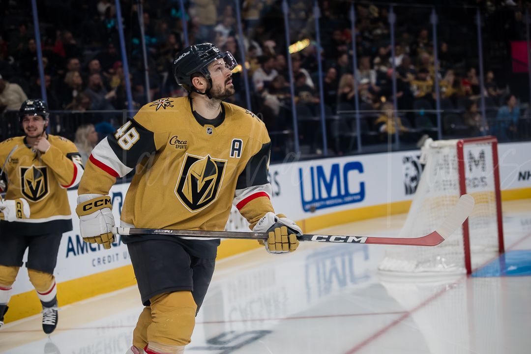 Vegas Golden Knights players in gold uniforms skate on the ice during a hockey match.