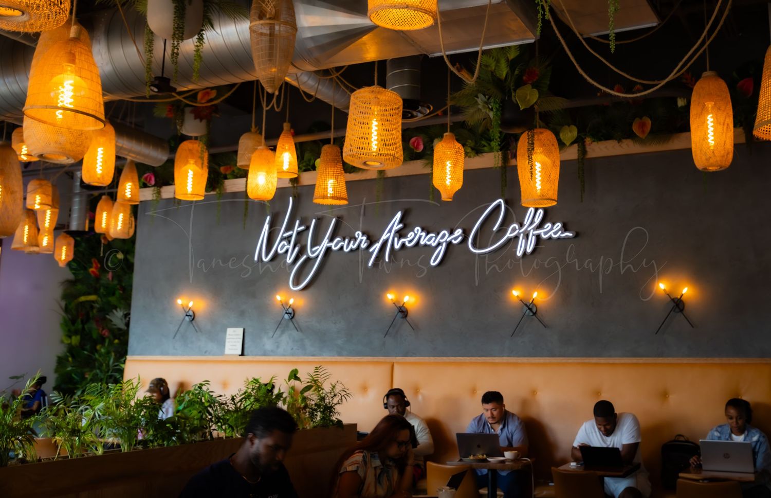 Row of orange pendant lights hanging from ceiling in modern restaurant setting.