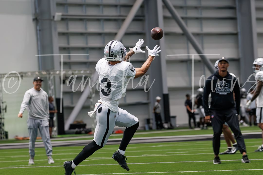 Raiders player catches a football during an indoor NFL practice session at the team facility.