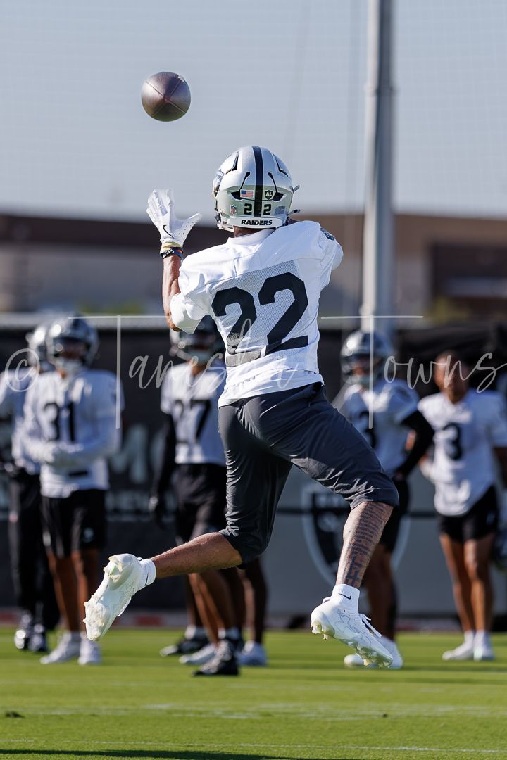 Las Vegas Raiders player #22 reaches up to catch a pass during outdoor training camp practice.