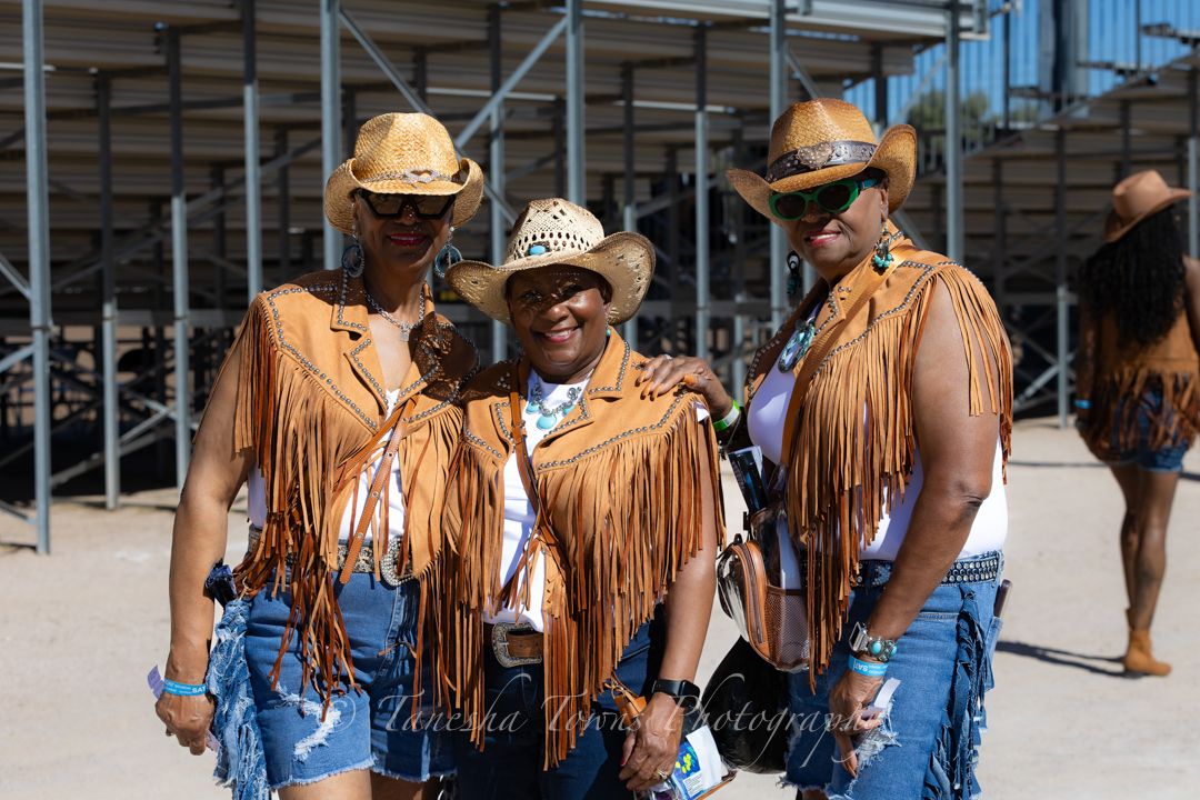 Cowgirls in matching denim and fringe outfits line up at rodeo event.