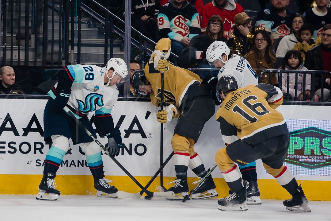Players scramble for the puck along the boards during an NHL hockey match.