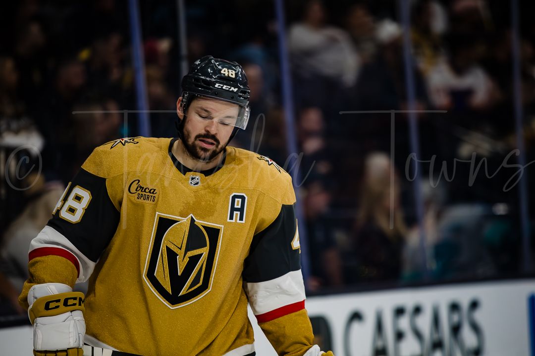 Vegas Golden Knights player in gold jersey with number 18 and alternate captain 'A' patch skates during NHL game.
