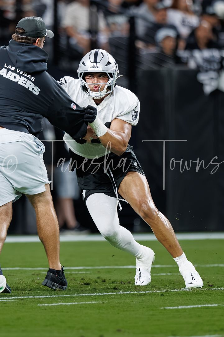 Las Vegas Raiders player in white uniform runs a drill during football practice at Allegiant Stadium.