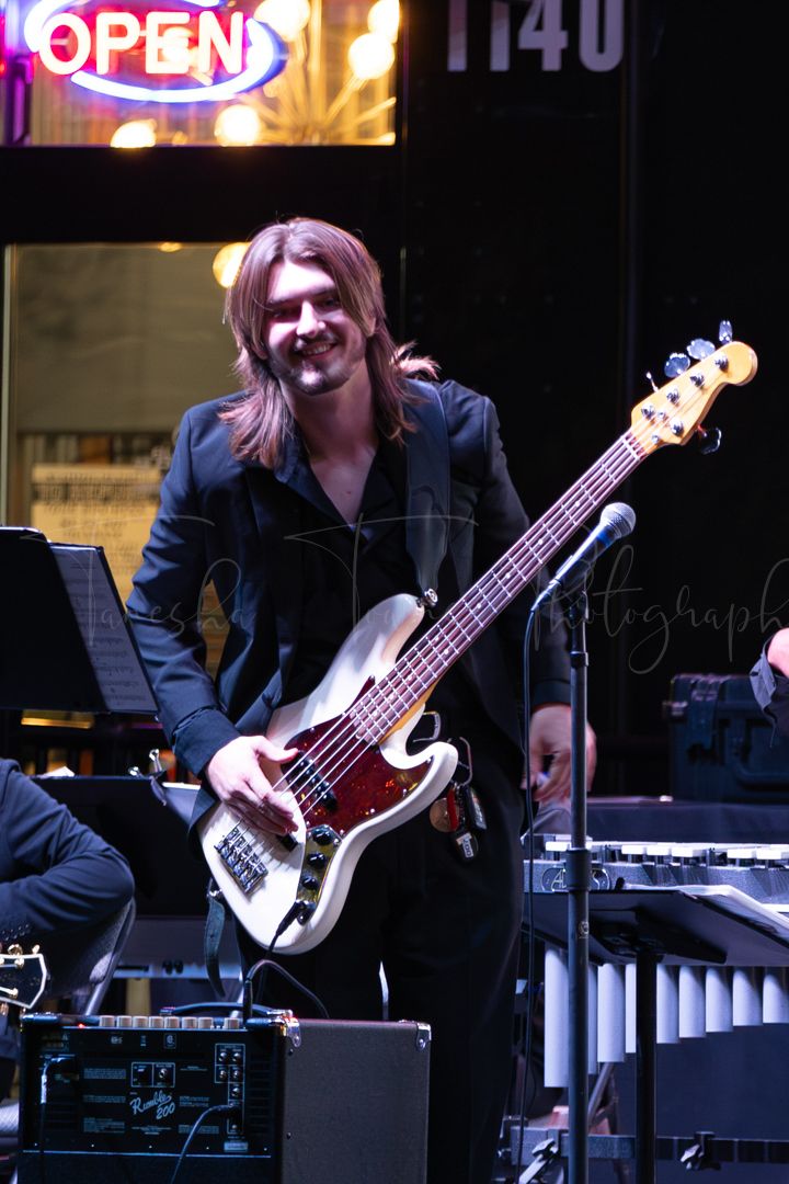 Bass guitarist performs on stage during a nighttime concert with professional lighting.