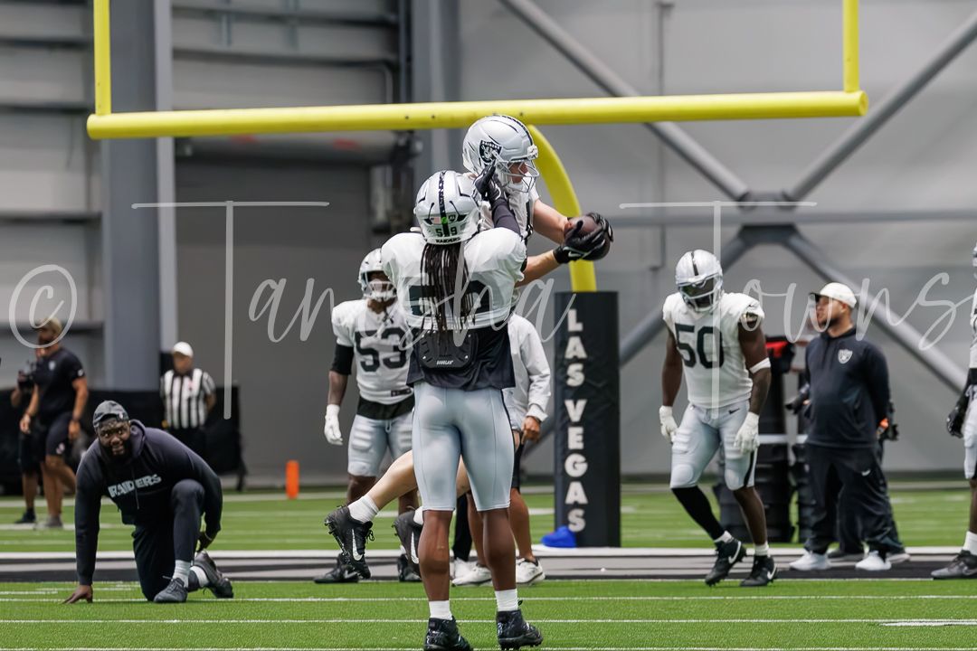 Las Vegas Raiders players practice drills inside an indoor football facility during training camp.