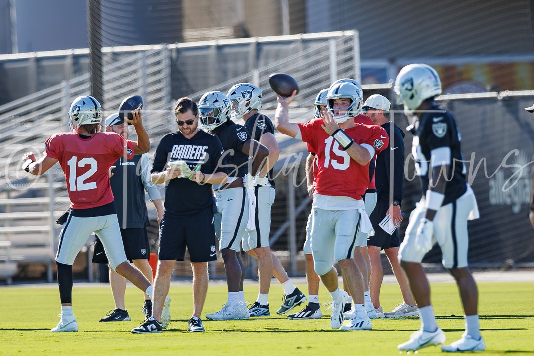 NFL players in Raiders uniforms practice passing drills on the field, wearing numbers 12 and 15 jerseys.