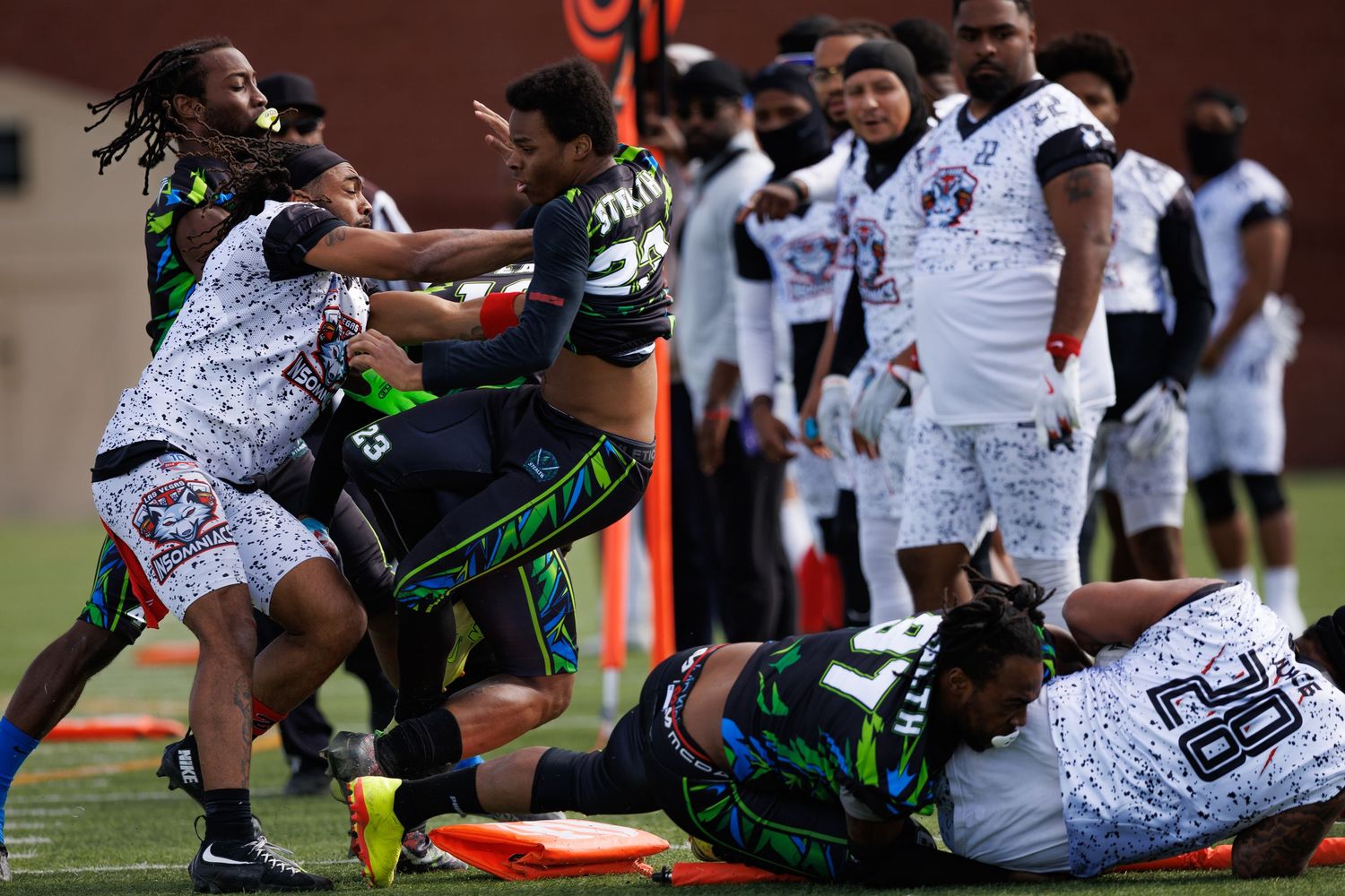 Flag football players engage in an intense on-field altercation during a competitive game on an orange turf field.