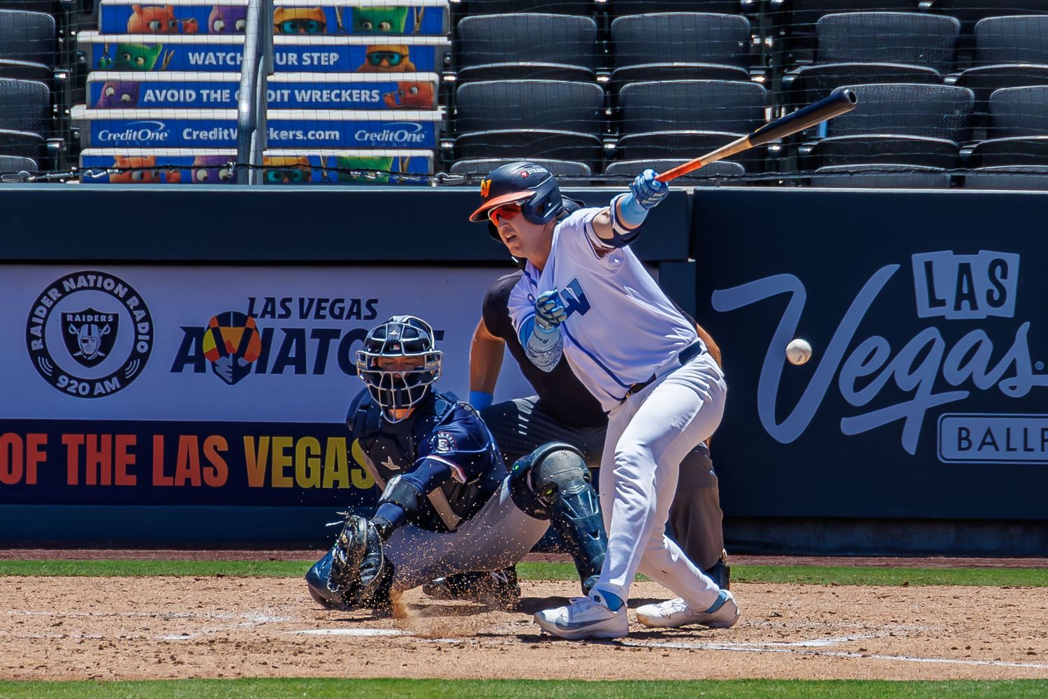Baseball batter swinging at pitch during Las Vegas Aviators game with catcher and umpire at home plate.