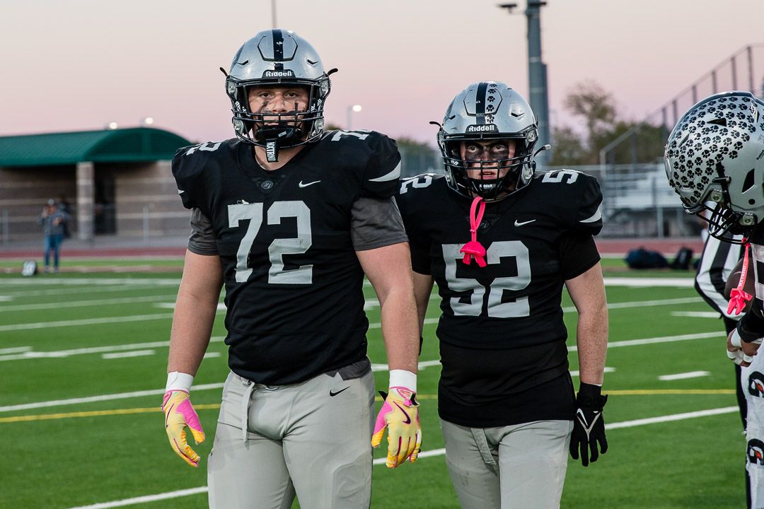 Players in black and white uniforms prepare for action on the football field.