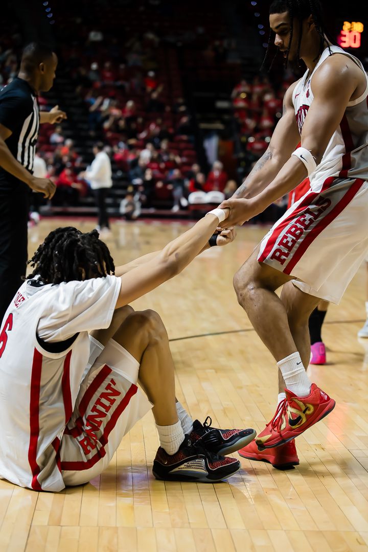 Basketball players' legs and shoes on a wooden court floor during a game.