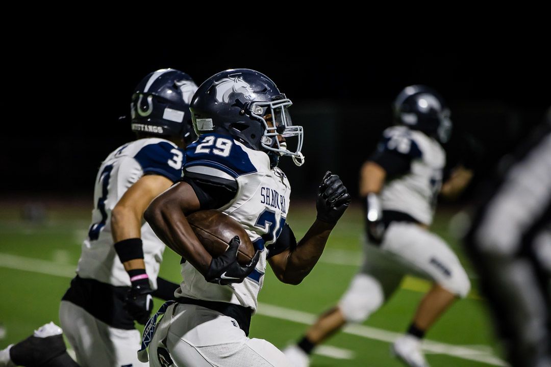 Football players from opposing teams collide during a running play.