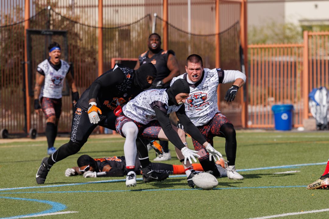 Flag football players compete intensely on a green turf field during an outdoor game.