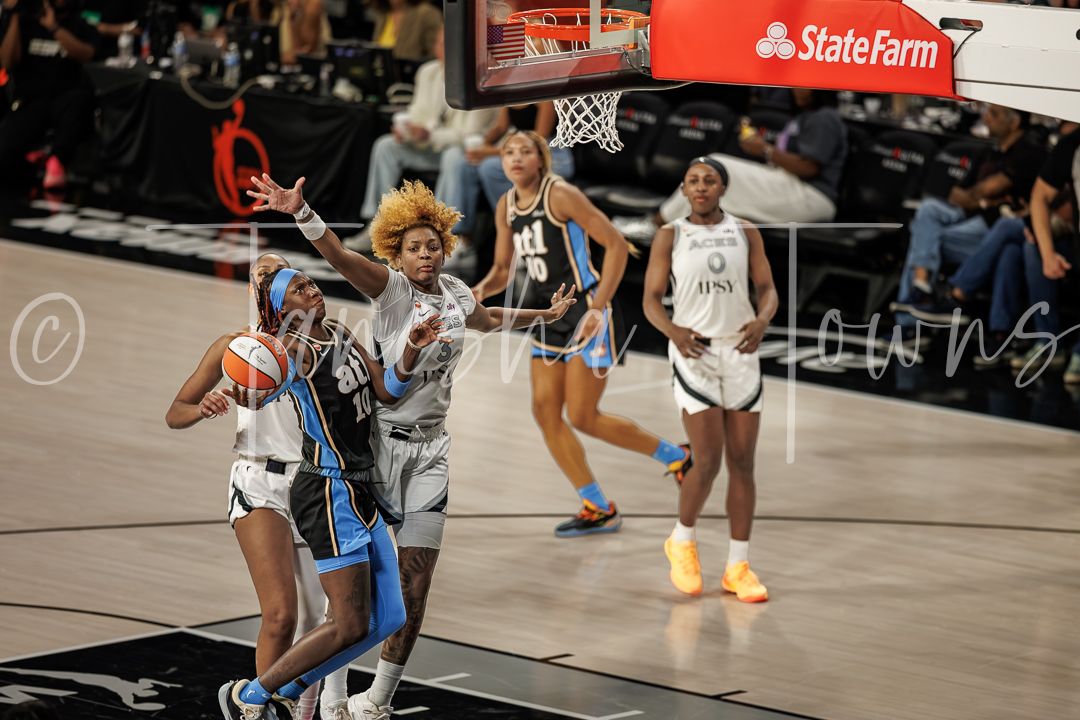 WNBA players compete in a fast-paced basketball game with State Farm arena signage visible in the background.