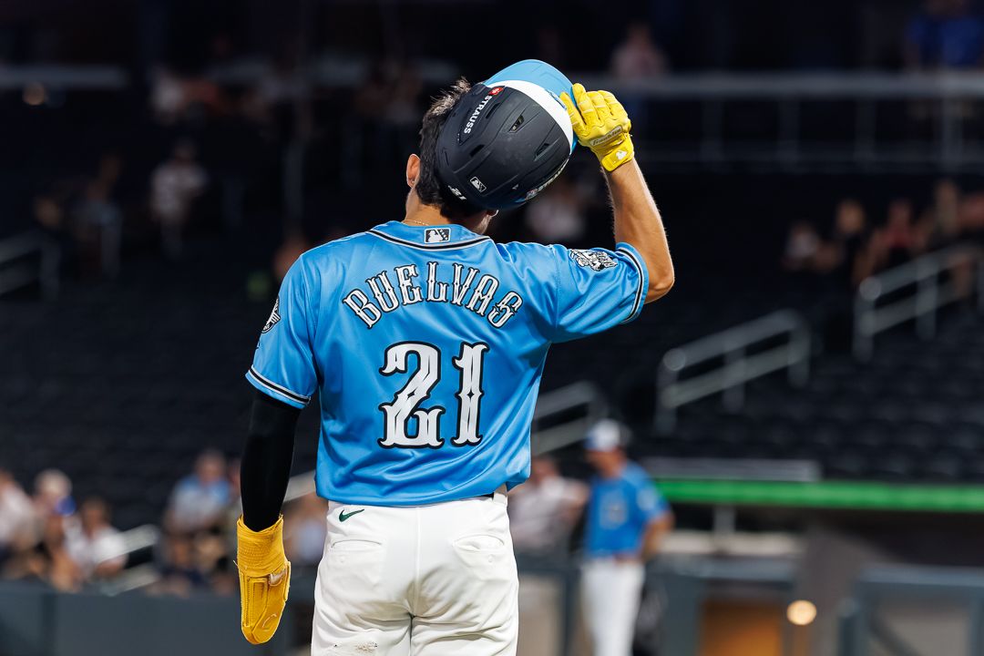 Baseball player #21 Cuellar in teal jersey tips helmet walking away on field.
