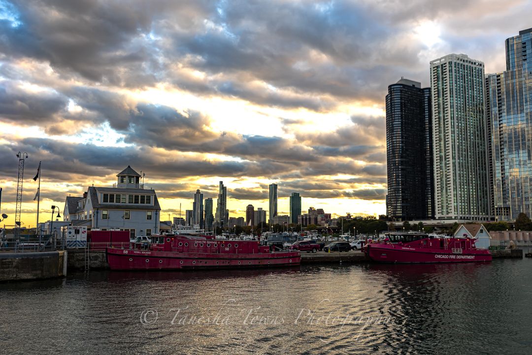 Panoramic cityscape of Chicago's waterfront at dusk with dramatic clouds and illuminated skyscrapers reflecting on the river.