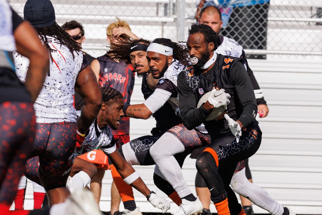 Athletes compete in an intense flag football game, with players in black and orange uniforms scrambling on the field.