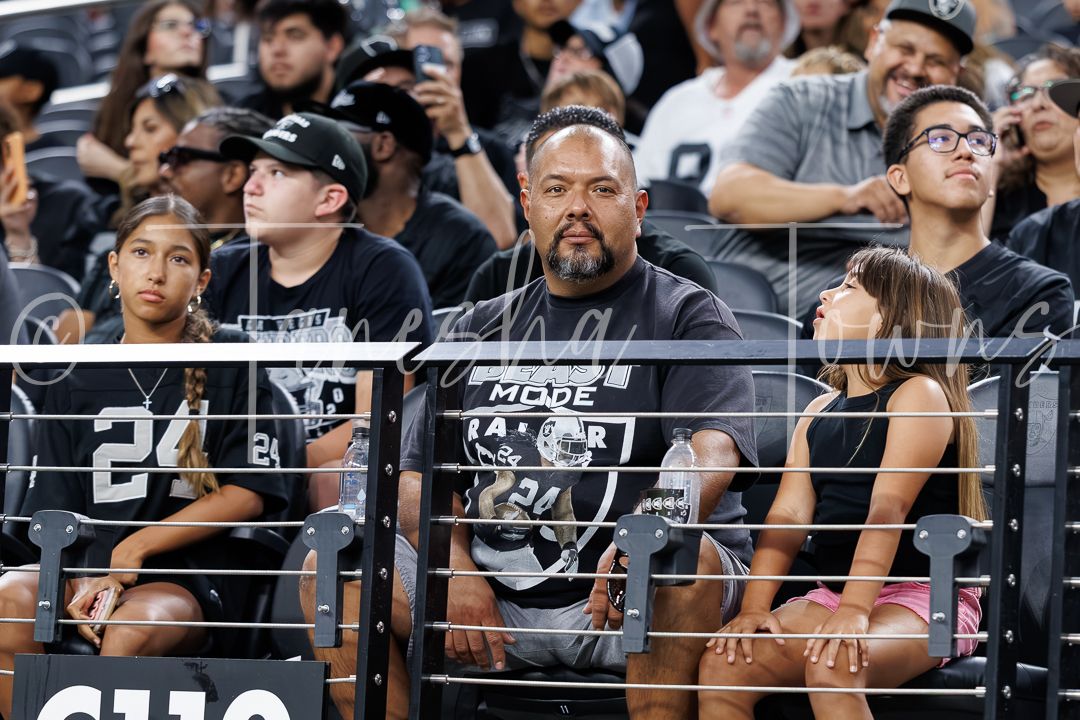 Las Vegas Raiders fans in black team gear watch the action from the stands at Allegiant Stadium.