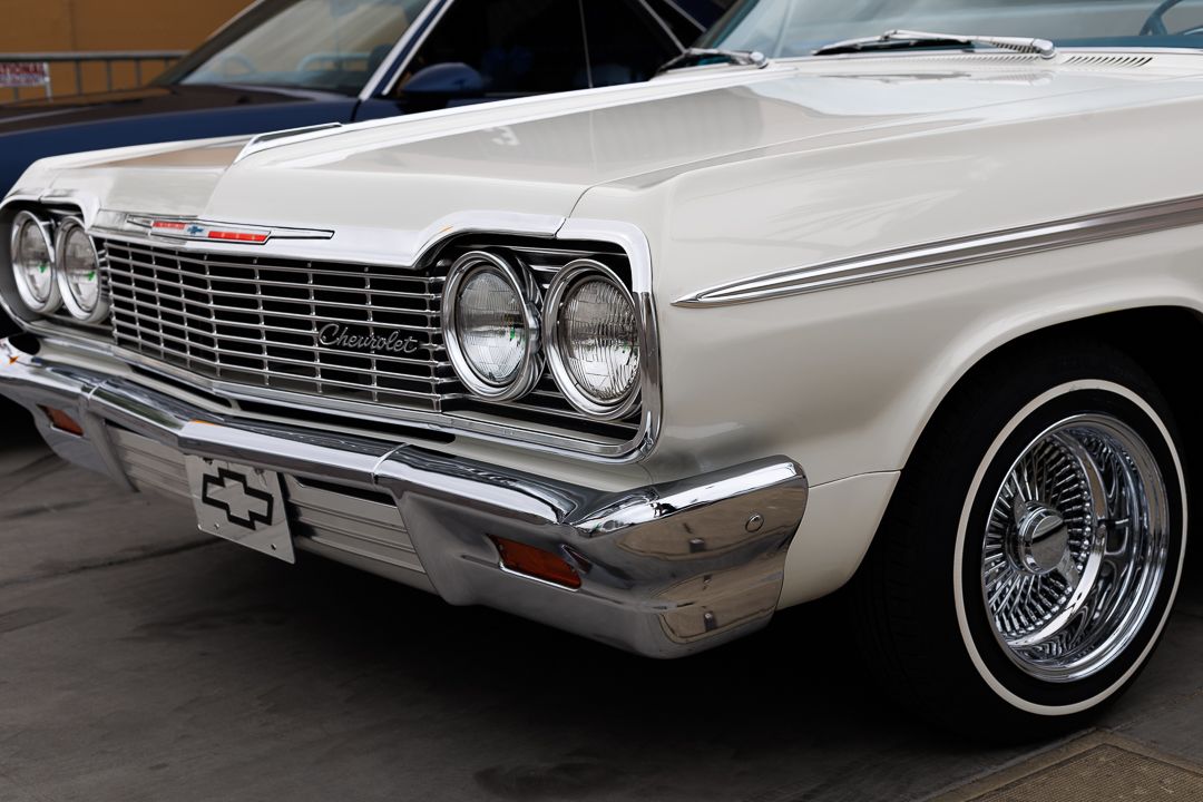 Classic white 1964 Chevrolet Impala with chrome grille and wire spoke hubcaps.