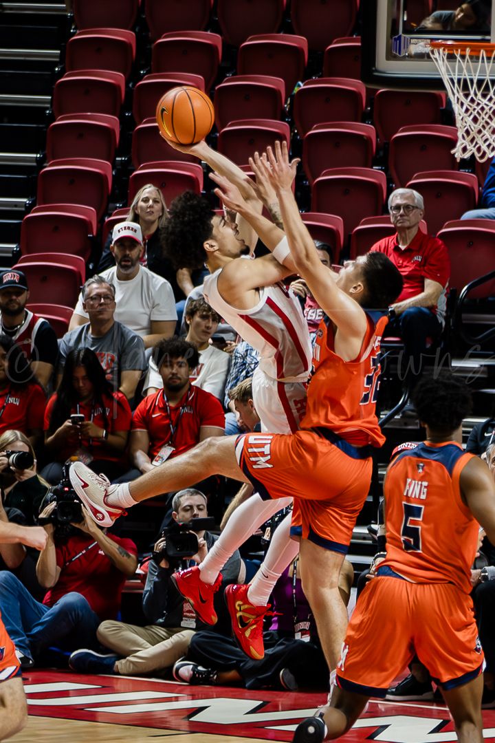 Multiple players battle for a rebound during intense basketball action on the court.
