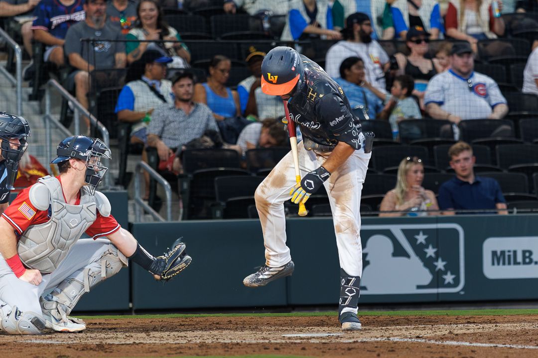 Baseball batter makes contact with a pitch during a MiLB night game.