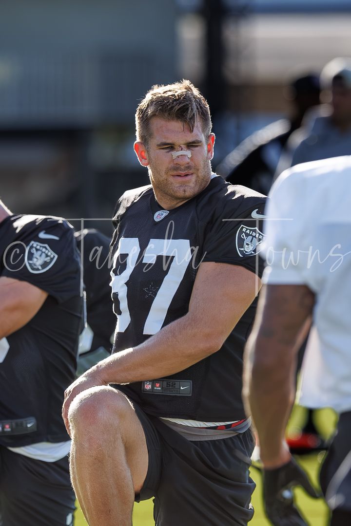 Raiders player #87 in black jersey stretching on sideline during NFL practice.