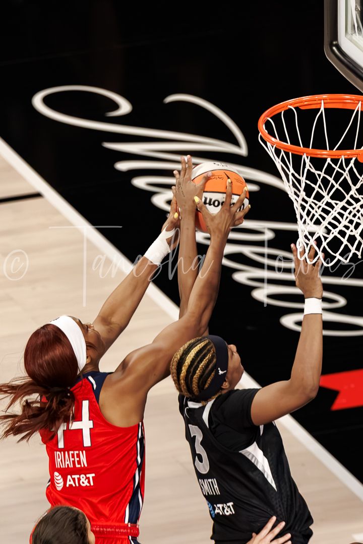 WNBA players Briafen and Smith battle for a rebound near the basket during a competitive game.