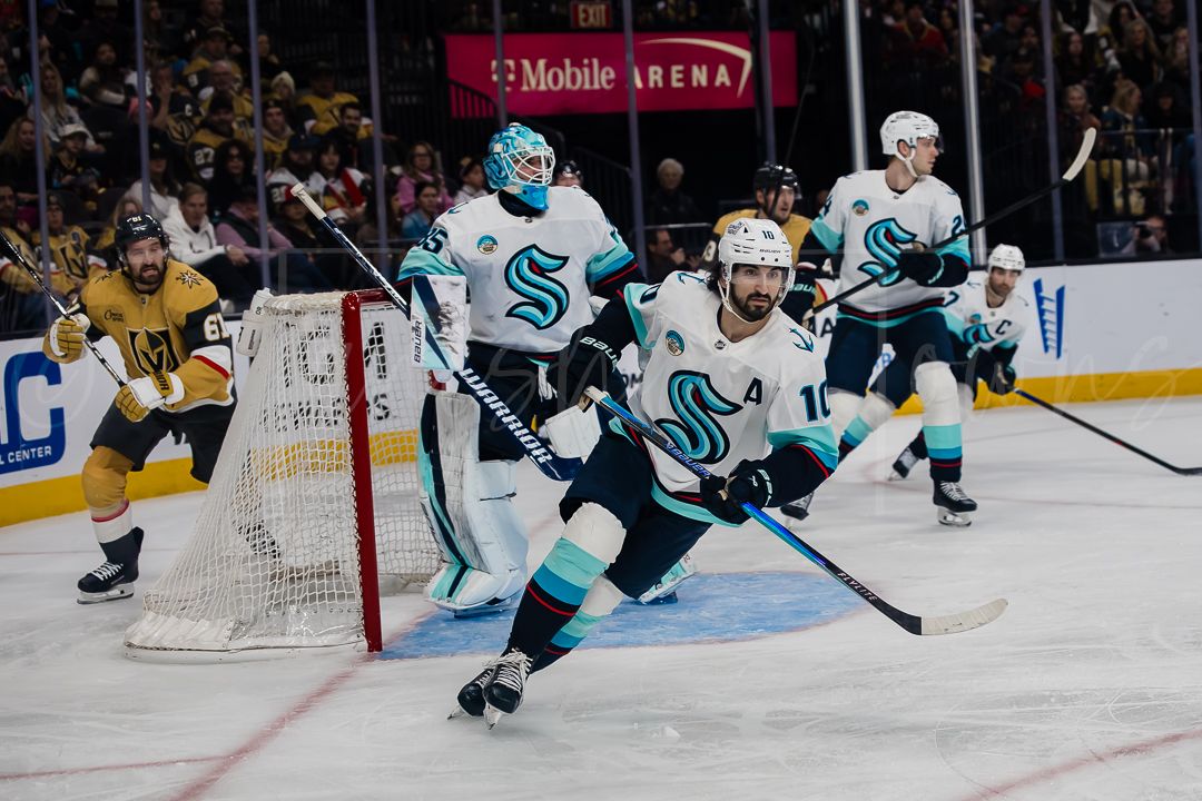 NHL hockey players from Seattle Kraken and Vegas Golden Knights battle for the puck during an intense game.