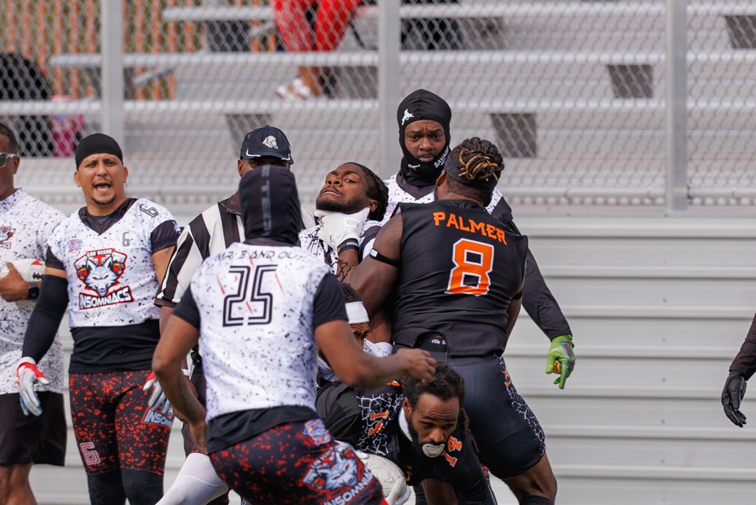 Football players collide during an intense tackle play, with player number 8 Palmer in orange and black uniform.