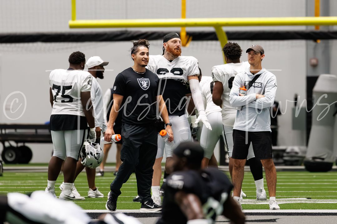 Las Vegas Raiders coaches and staff observe players during indoor training camp practice session.