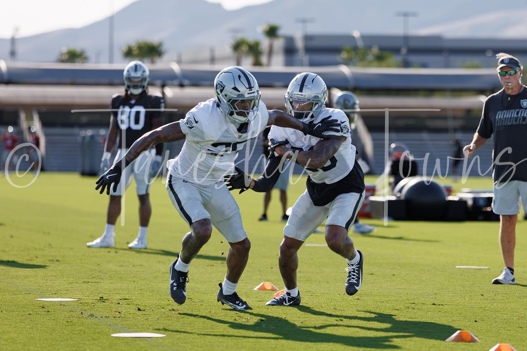 Las Vegas Raiders players run blocking drills at outdoor training camp practice.