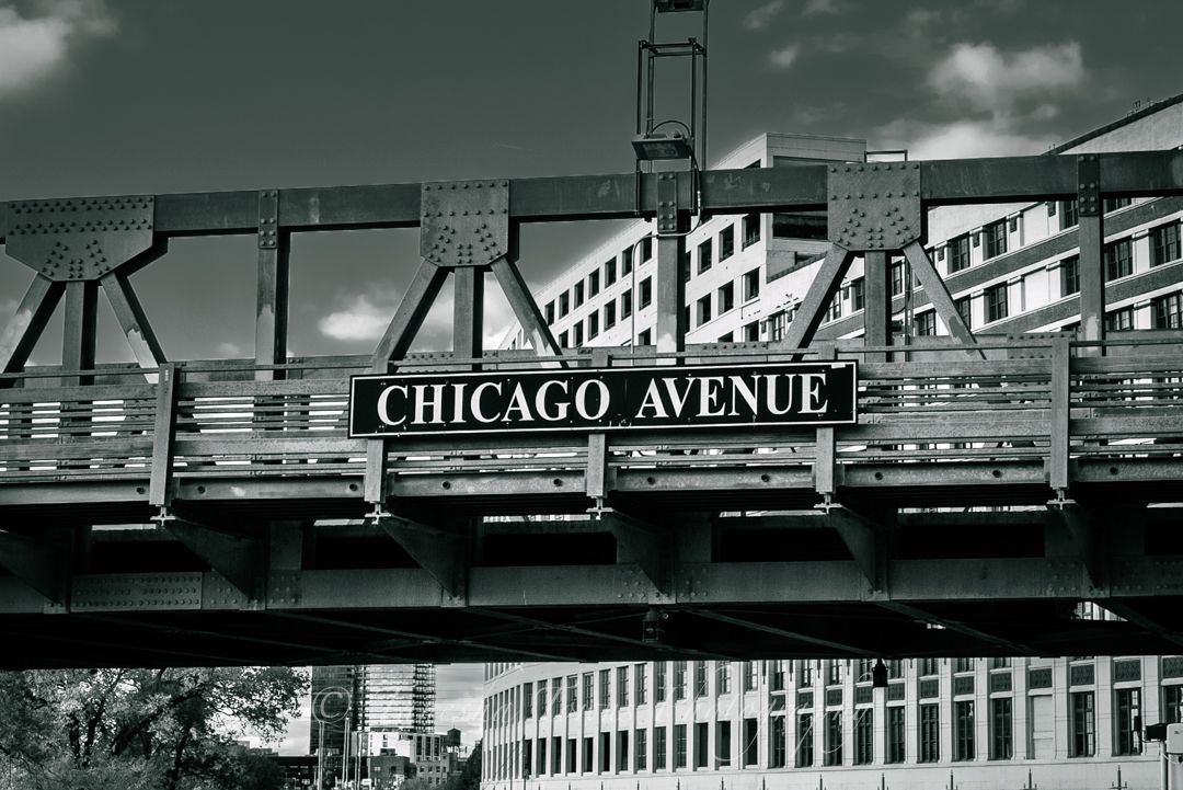 Panoramic black and white cityscape showing Chicago's elevated train tracks and urban architecture along Chicago Avenue.